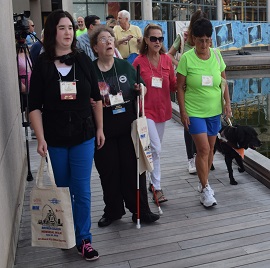 2018 Walk walking along a wooden sidewalk is DJ McIntyre, Karyn Campbell, a lady in a red shirt, and Debbie Young.
